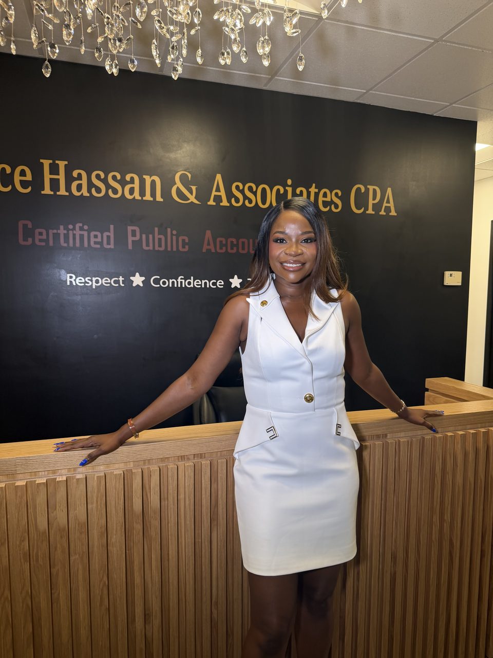 Bernice Hassan, CPA, principal owner, standing at the reception desk of the firm's Columbia, Maryland office beneath the wall lettering reading Bernice Hassan & Associates CPA.